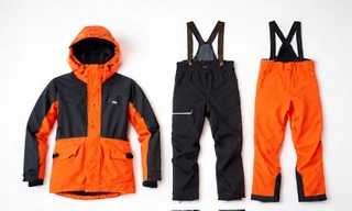 A set of technical ski apparel including a waterproof jacket, pants, and base layers, laid out neatly.
